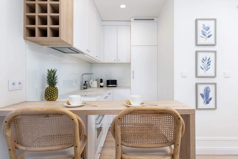 Bright kitchen and dining area with rattan chairs, wooden finishes, and botanical wall art for a natural feel.

