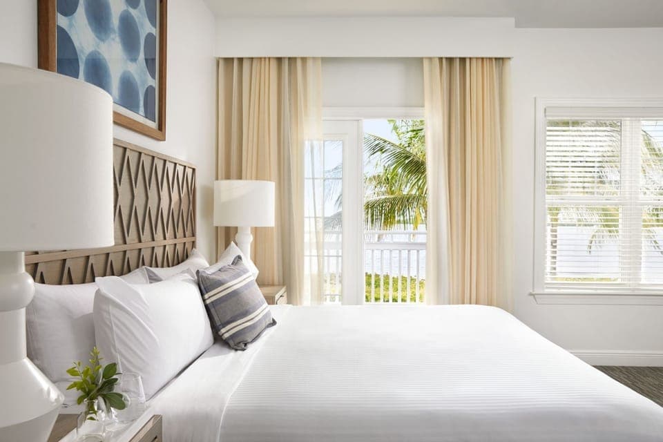 Sink into crisp linens beside soft drapes and airy windows.