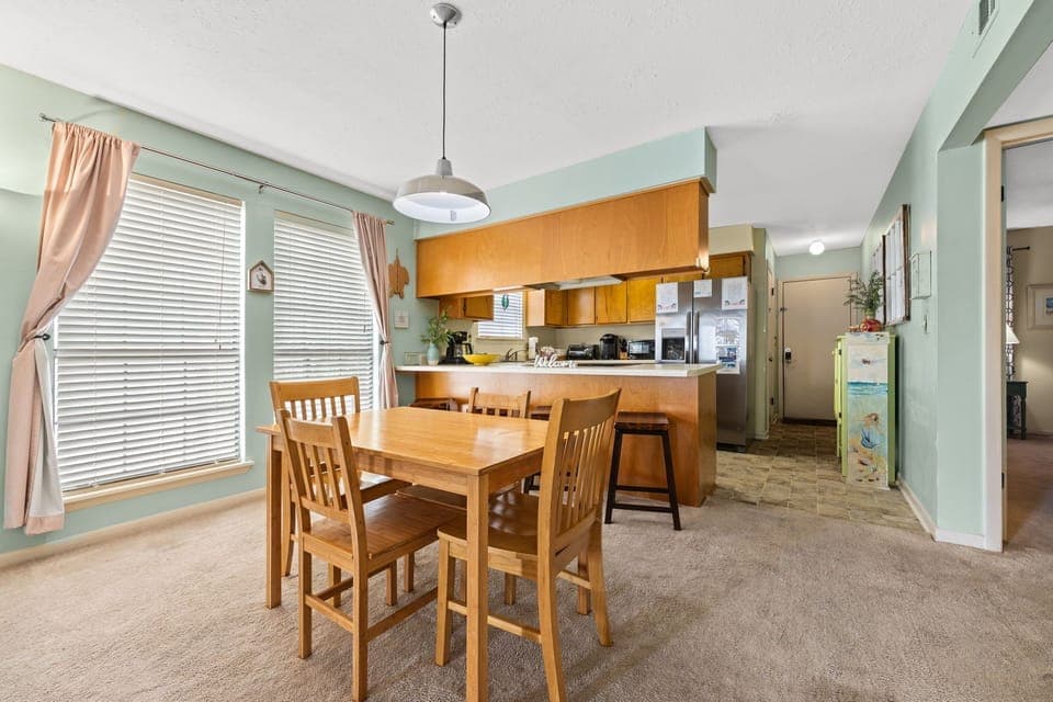 Gather around your spacious dining table in this bright, airy space where warm wood tones meet soothing mint walls, creating the perfect atmosphere for memorable meals together.