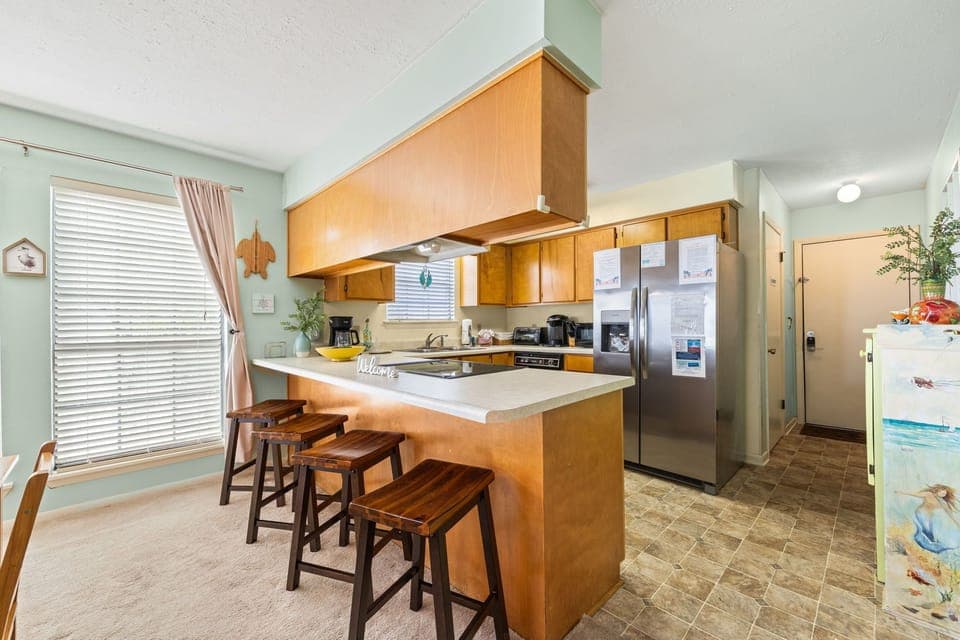Your fully equipped kitchen features warm wood cabinetry, modern appliances, and a breakfast bar where you can start your day with coffee.
