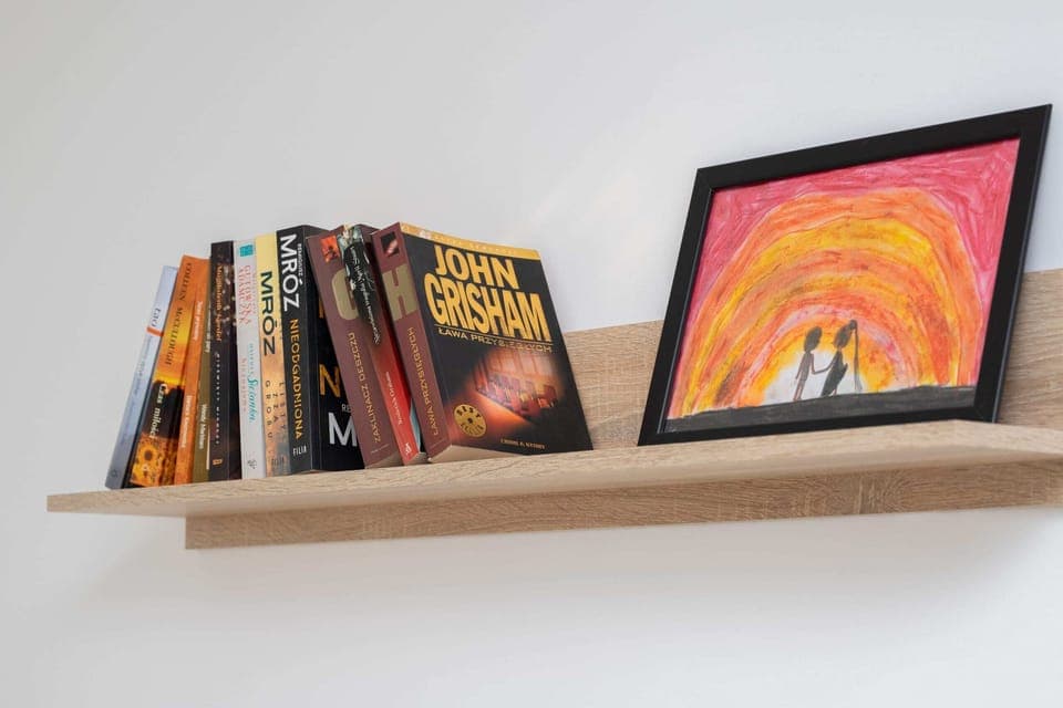 A closer look at a bookshelf with books and an artistic painting for a decorative touch.