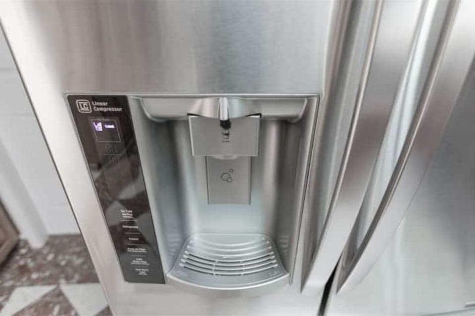 The LG stainless steel fridge has a built-in water dispenser.