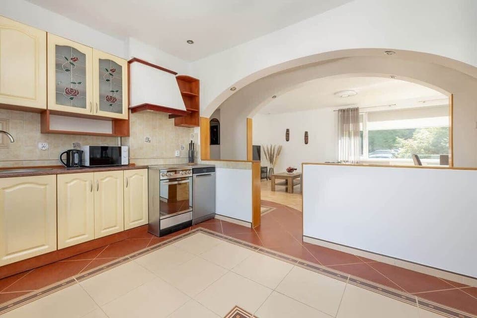 Fully equipped kitchen with ample cabinet space, tiled flooring, and all the essential appliances you need for home cooking.

