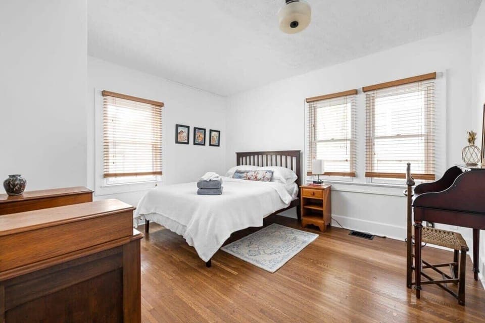 A queen bed paired with a bedside table, enhanced by wall-mounted frames, and complemented with a dresser for both convenience and a touch of style.