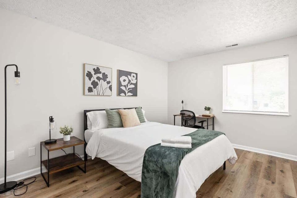 We've created a cozy space with a bed adorned in soft pillows and fresh linens. Bedside tables with lamps and a few frames on the wall enhance the ambiance, ensuring a restful sleep in our carefully designed bedroom.