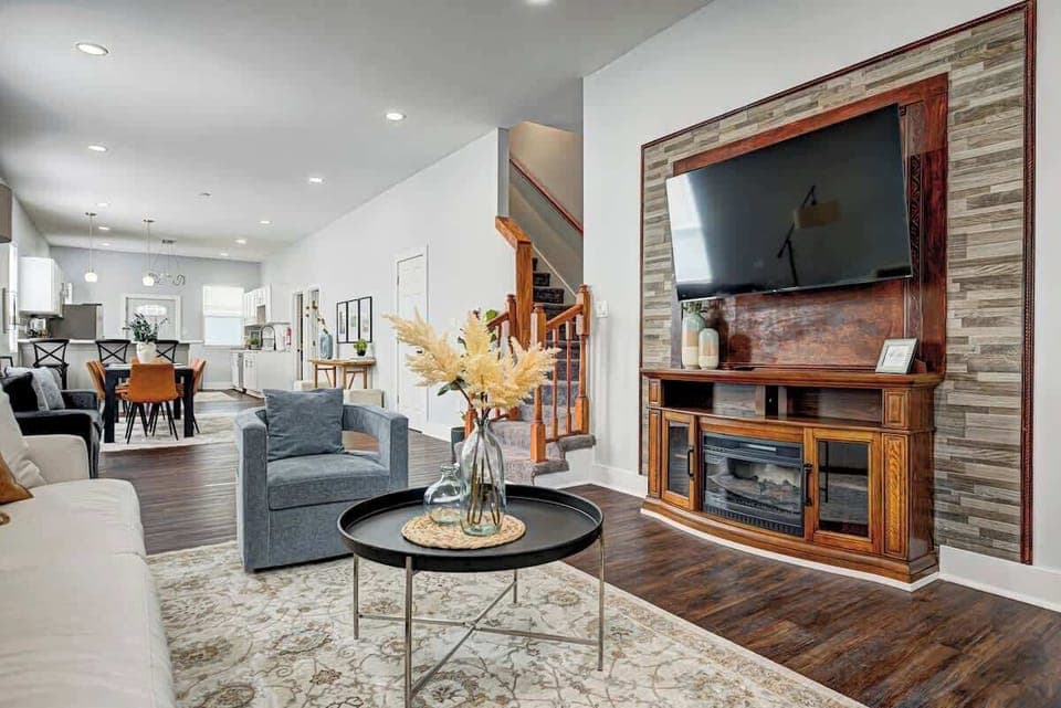 Cozy and inviting, this living room features a plush sofa and a comfy swivel chair, perfect for relaxation. Several poufs offer extra seating, while a large smart TV sets the scene for movie nights and entertaining!