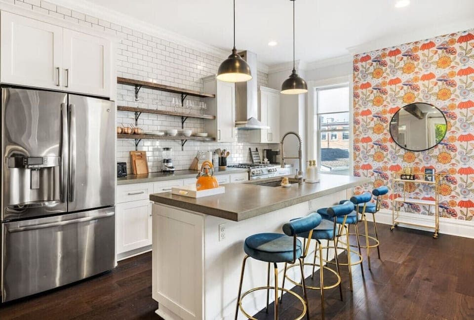 A well-appointed and roomy kitchen featuring a generous kitchen island boasting bar seating for four, accompanied by a convenient beverage cart.