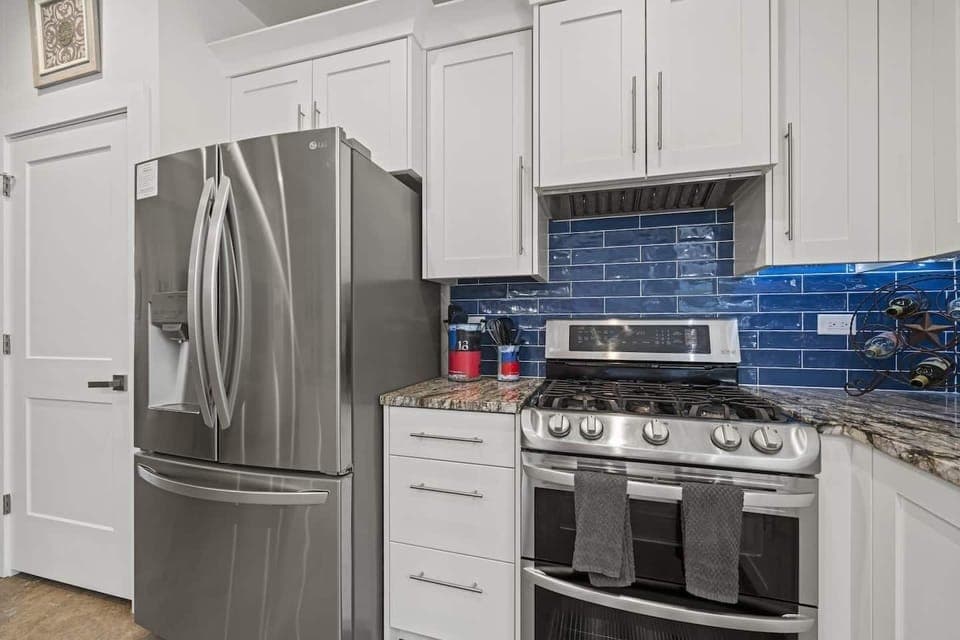 "Modern kitchen at Wimberley Retreat — stainless steel appliances, vibrant blue backsplash, and sleek design for a stylish Texas stay.