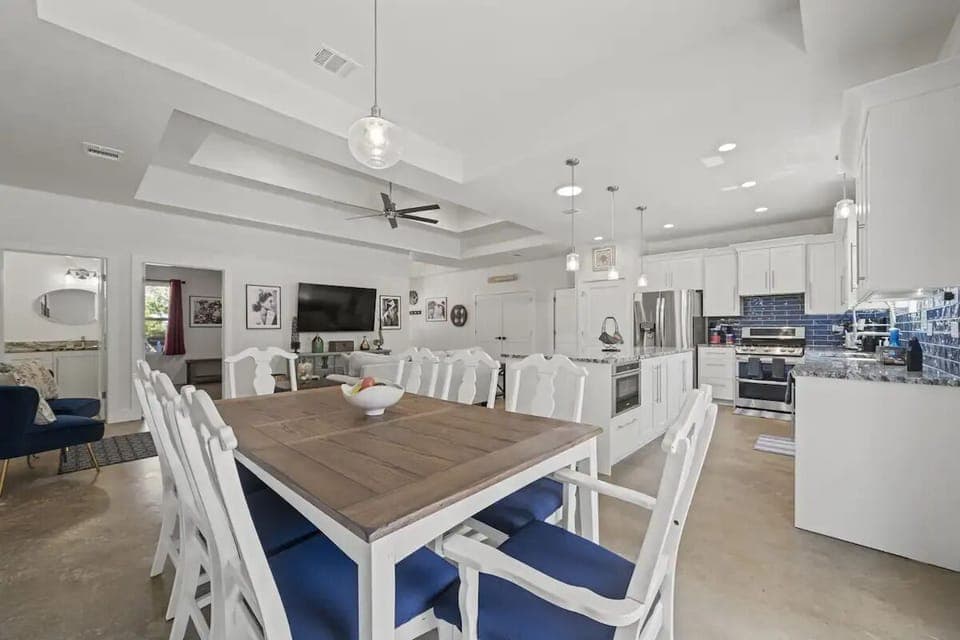 Enjoy meals and moments in this open-concept space featuring stainless steel appliances, blue-cushioned seating, and bright, airy design—your stylish retreat in Wimberley, Texas.