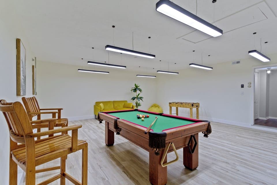 Pool table-centered space with cozy seating and bright lighting.