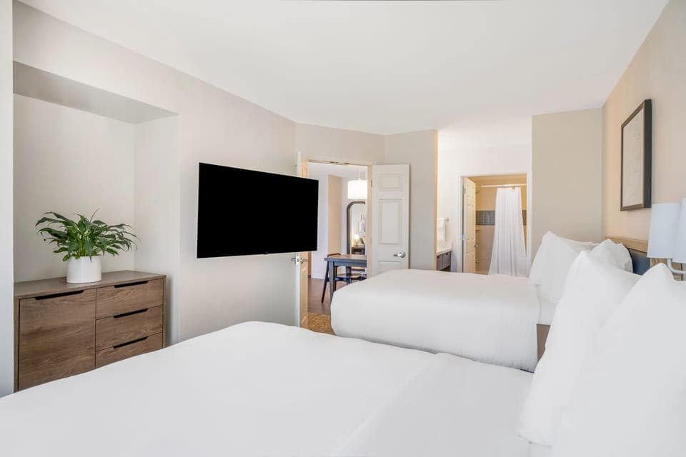 Unwind in a sunlit bedroom with crisp linens and space.