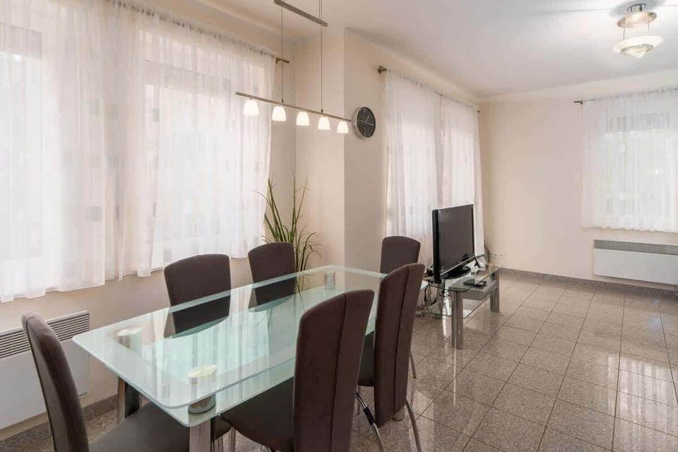 A dining area with a glass table and chairs, situated near large windows for natural light.
