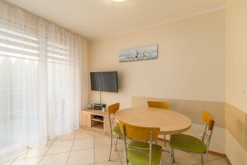 A bright space with a dining table, green sofa, and access to the balcony, creating a relaxing atmosphere.

