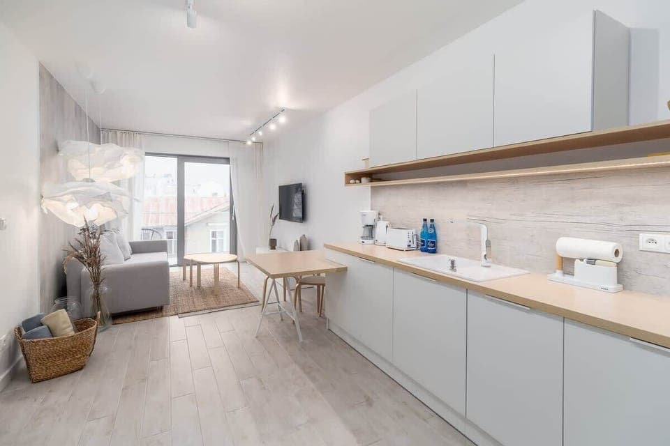 A sleek kitchen with white cabinets, open shelving, and a spacious layout extending to the dining area.
