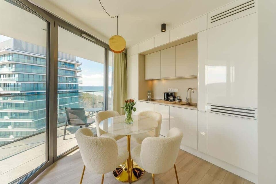 The living area features a sleek dining table and a flat-screen television.