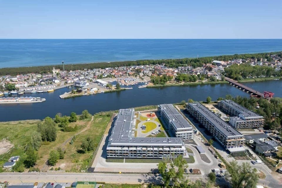 Aerial view of a residential complex, emphasizing its proximity to the water and surrounding nature.
