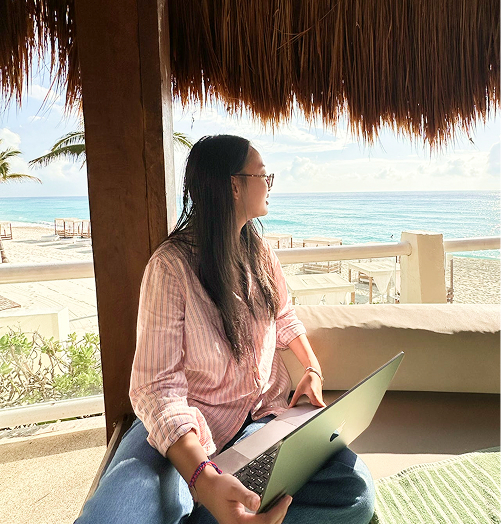 Woman working on laptop on beach